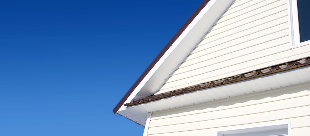 White soffit and fascia under a gable with cream vinyl siding