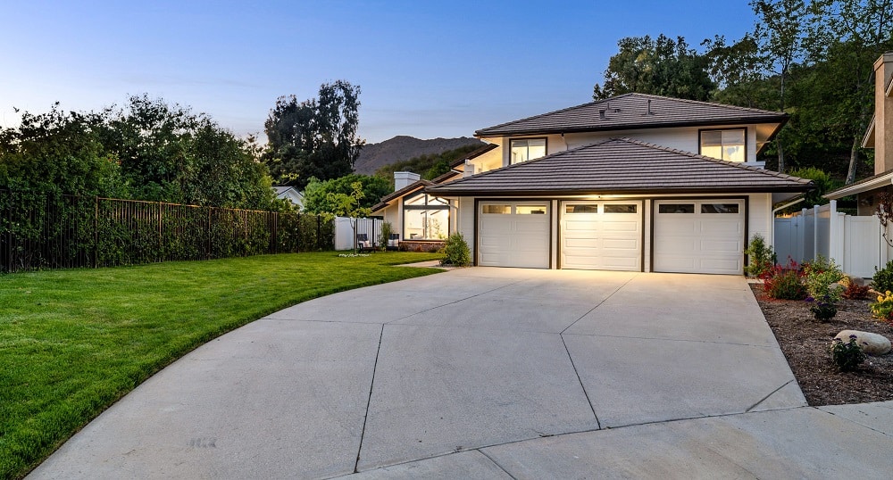 Wide concrete driveway leading to a three-car garage