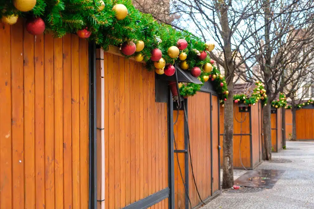 Christmas market stalls decorated with pine branch and colorful toy balls.