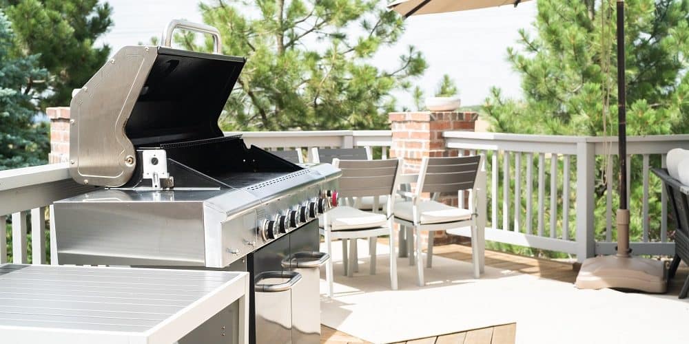 Outdoor six-burner gas grill on the back patio of a luxury single-family home.