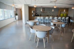 Finished office breakroom with round tables and pendant lights