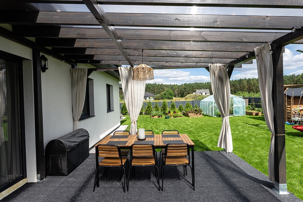 The terrace behind the house is made of beams, the roof is covered with polycarbonate.